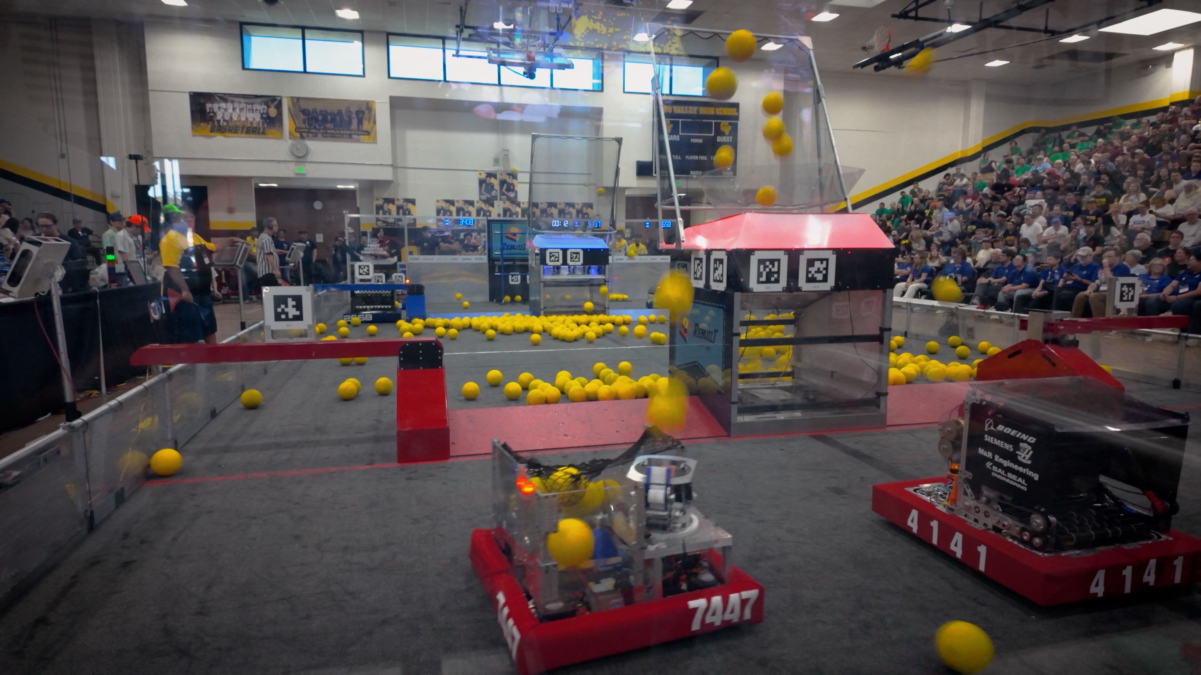Our 2026 robot competing on the field during a match with yellow game pieces in flight.