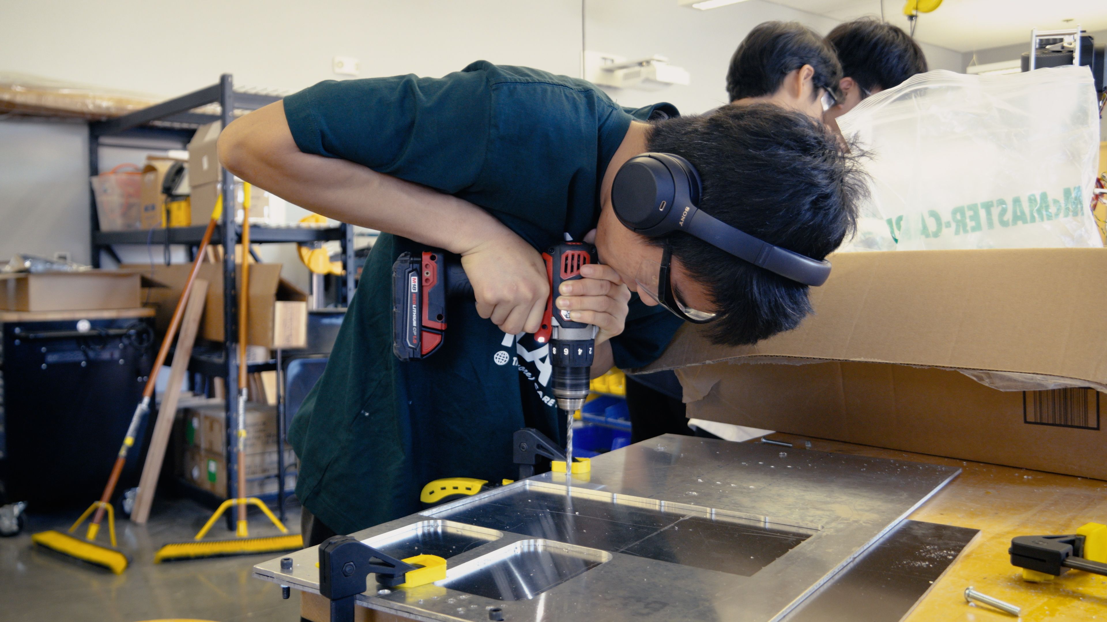 A team member drilling into a robot panel during fabrication.